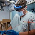 a surgeon wears glasses and a mask while operating on a patient