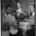 A black-and-white photograph of two musicians playing drums with their hands and one playing the maracas