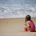 girl with a pail playing on the beach