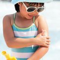 child applying sunscreen sunglasses hat protect